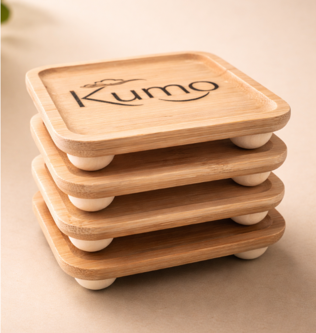 Stack of wooden coasters with 'Kumo' branding on a beige surface